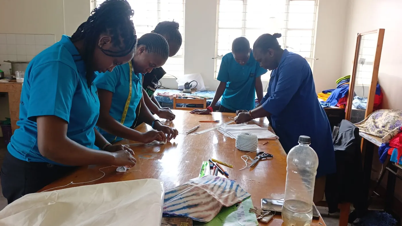 Fashion students measuring and marking fabric around a worktable