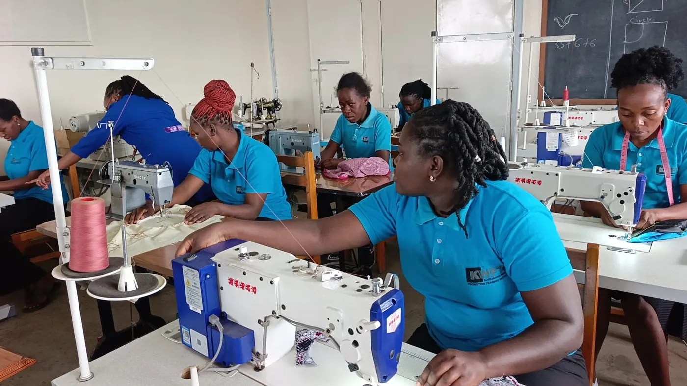 A tailoring student guiding fabric through an industrial sewing machine