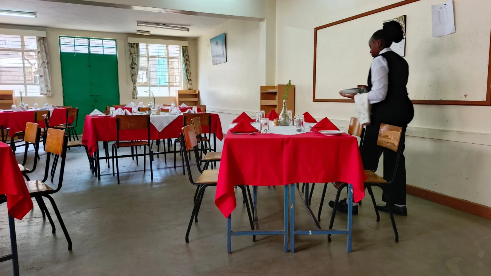 A KWPTI hospitality student preparing the restaurant dining room